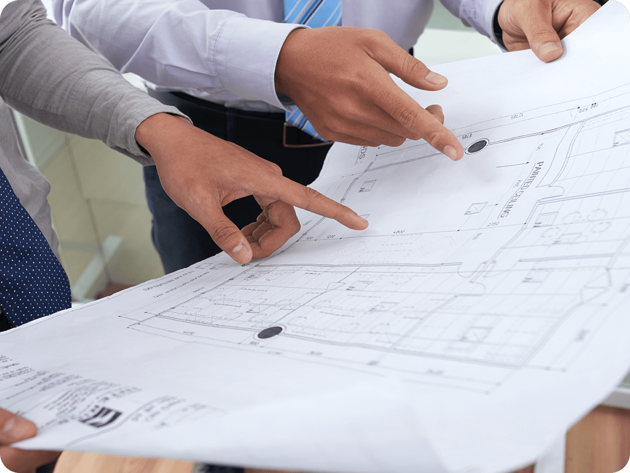 Hands pointing at architectural blueprint on table.