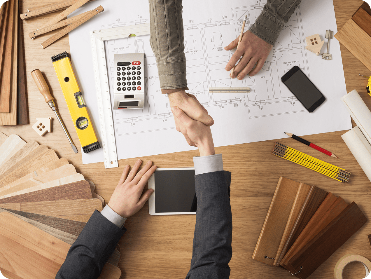 Handshake over architectural plans and materials.