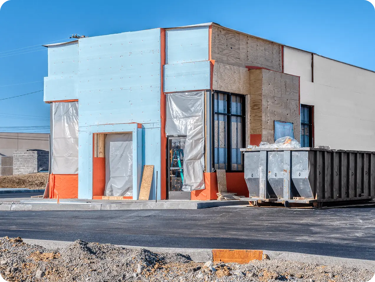 Plywood-clad commercial construction site with dumpster